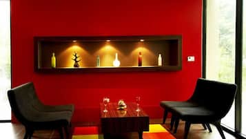 Ein modernes Zimmer mit roter Wand, zwei schwarzen Stühlen, einem Holztisch und einem Regal mit Dekoration.