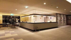 A hotel reception area with a counter, chairs, and a patterned carpet.