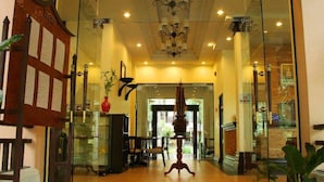 A hotel lobby with a chandelier, glass display cases, and a wooden reception desk. - Lecasa Bangsaen Hotel (Chonburi)