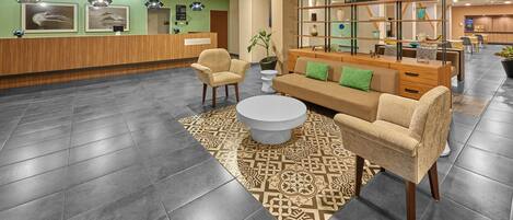 A modern lobby with a reception desk, seating area, and a coffee table.