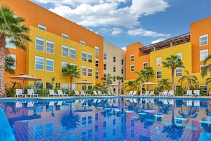 Un hotel con piscina, varios pisos y palmeras.