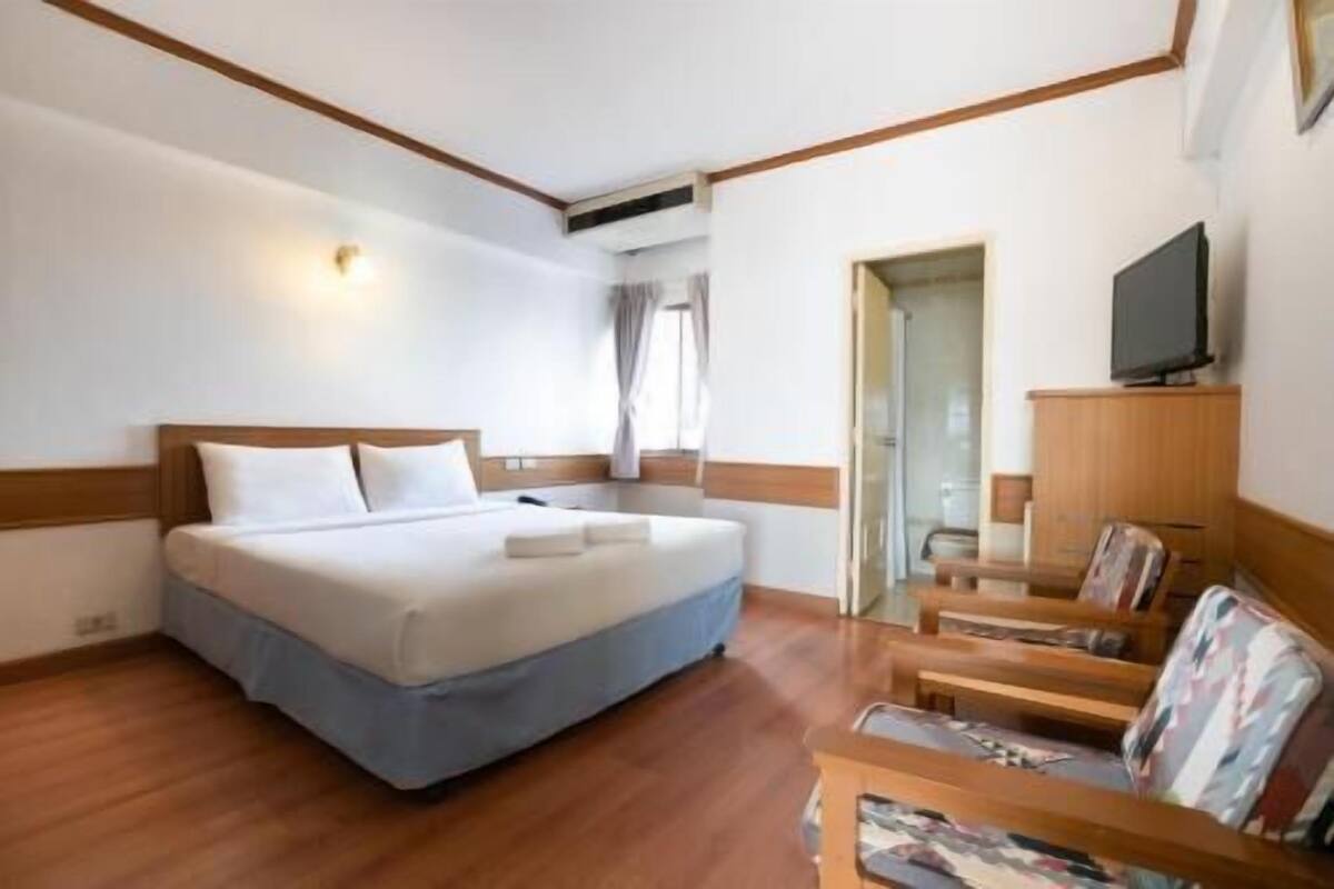 A hotel room with a bed, a TV, a wooden chair, and a desk.