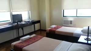 Habitación de hotel con dos camas, un escritorio, un televisor y un equipo de aire acondicionado.