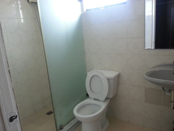 Un baño con inodoro, lavamanos y cabina de ducha de cristal.