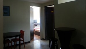 Una habitación con una mesa de comedor, sillas, un taburete pequeño, una cama y una puerta con la indicación 701 B.