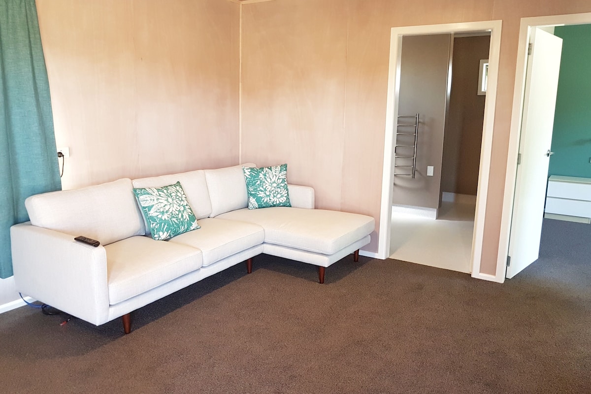 Ein weißes, modulares Sofa mit floralen Kissen in einem Raum mit beigen Wänden und Teppich.
