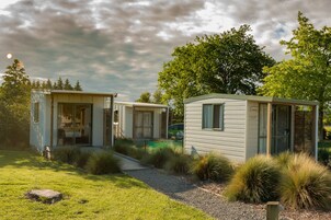 Dos casas móviles con un patio cubierto de césped y un árbol al fondo.