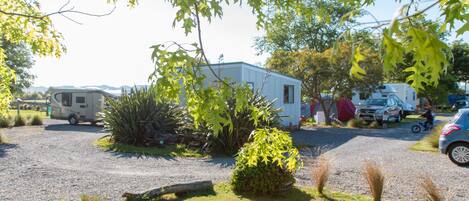 A campsite with RVs, a small building, and a gravel driveway.