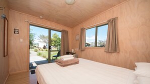Un dormitorio con una cama grande, paredes de madera y vistas al exterior.