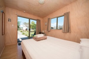 Un dormitorio con una cama grande, paredes de madera y vistas al exterior.