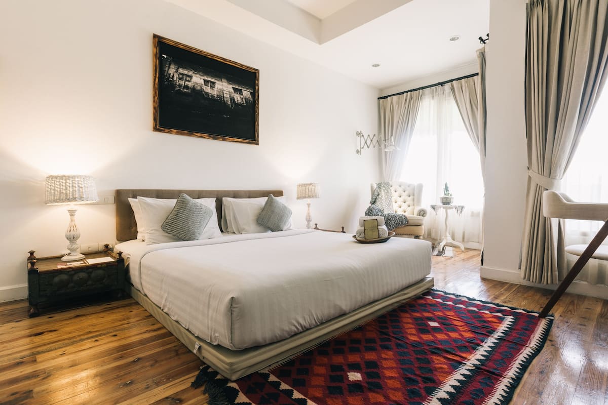 A bedroom with a large bed, a patterned rug, and a painting on the wall.