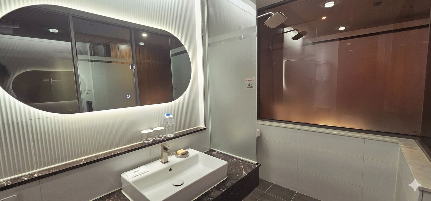 A modern bathroom with a large mirror, a sink, and a shower area.