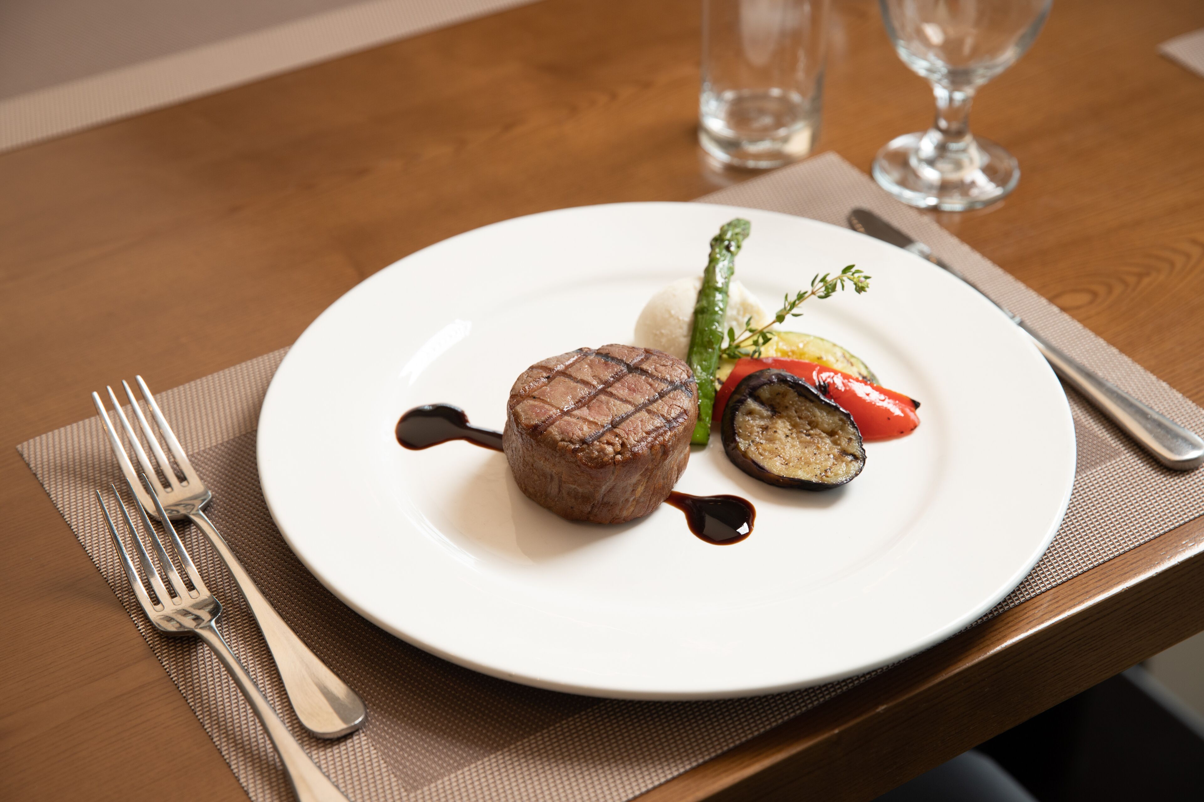 A plate of food on a wooden table with a fork and knife set to the side.