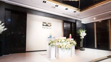 A modern reception area with a white reception desk, floral decorations, and a logo for 'Solaire'.