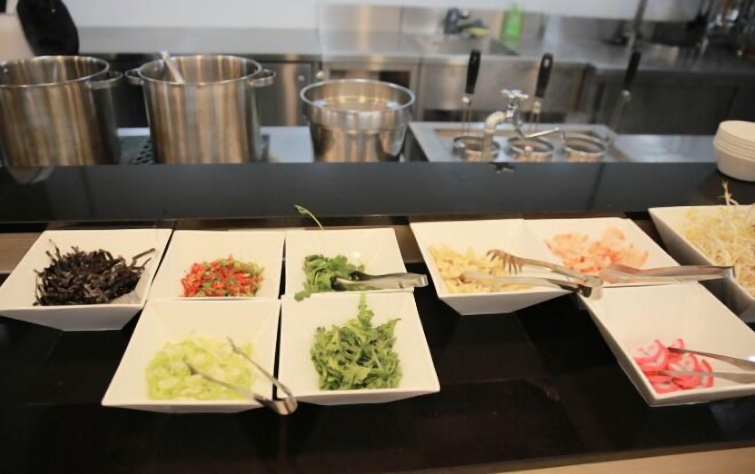A buffet with various food items in trays, including seafood, vegetables, and salads.