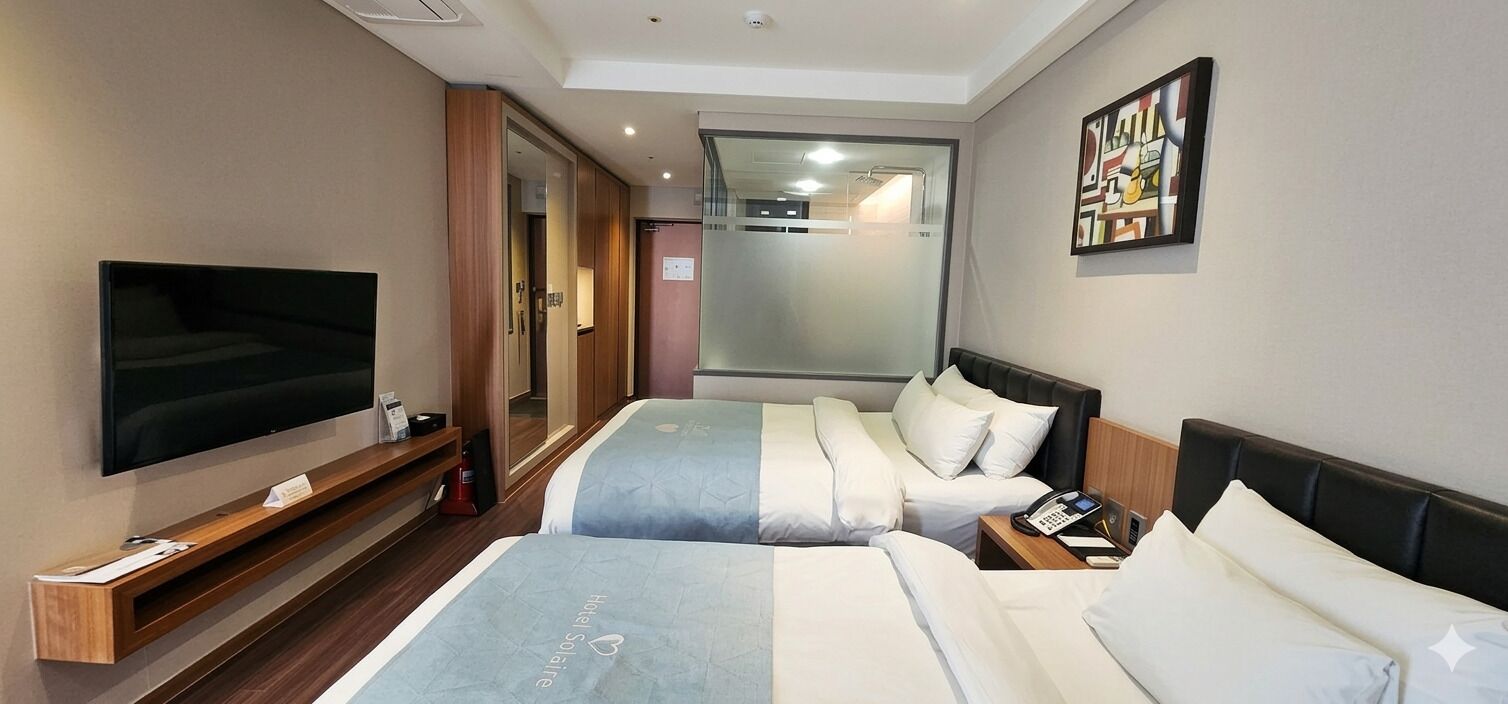 A hotel room with two beds, a TV, a bedside table with a phone, and a painting on the wall.