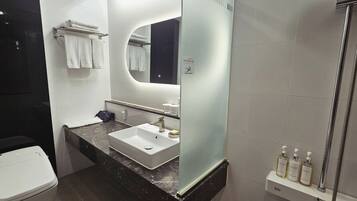 Un baño moderno con un lavamanos blanco, un espejo, toallero y zona de ducha.