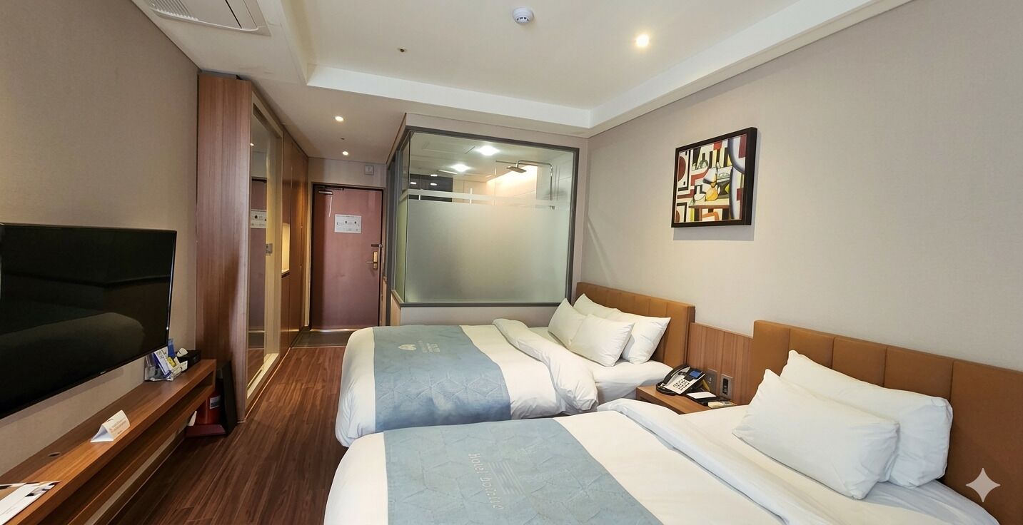Habitación de hotel con dos camas, televisor, teléfono y un cuadro en la pared.