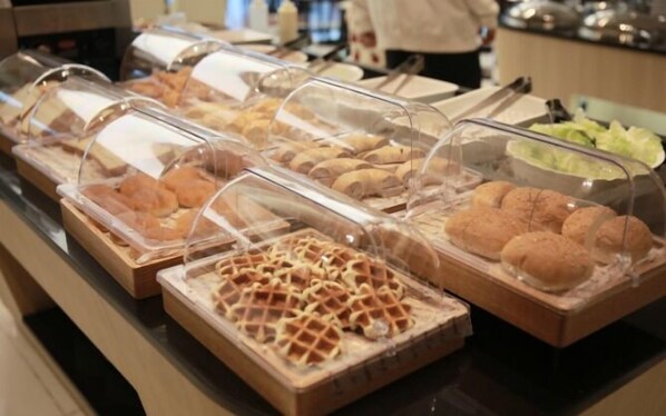 A buffet with various food items covered in clear plastic.