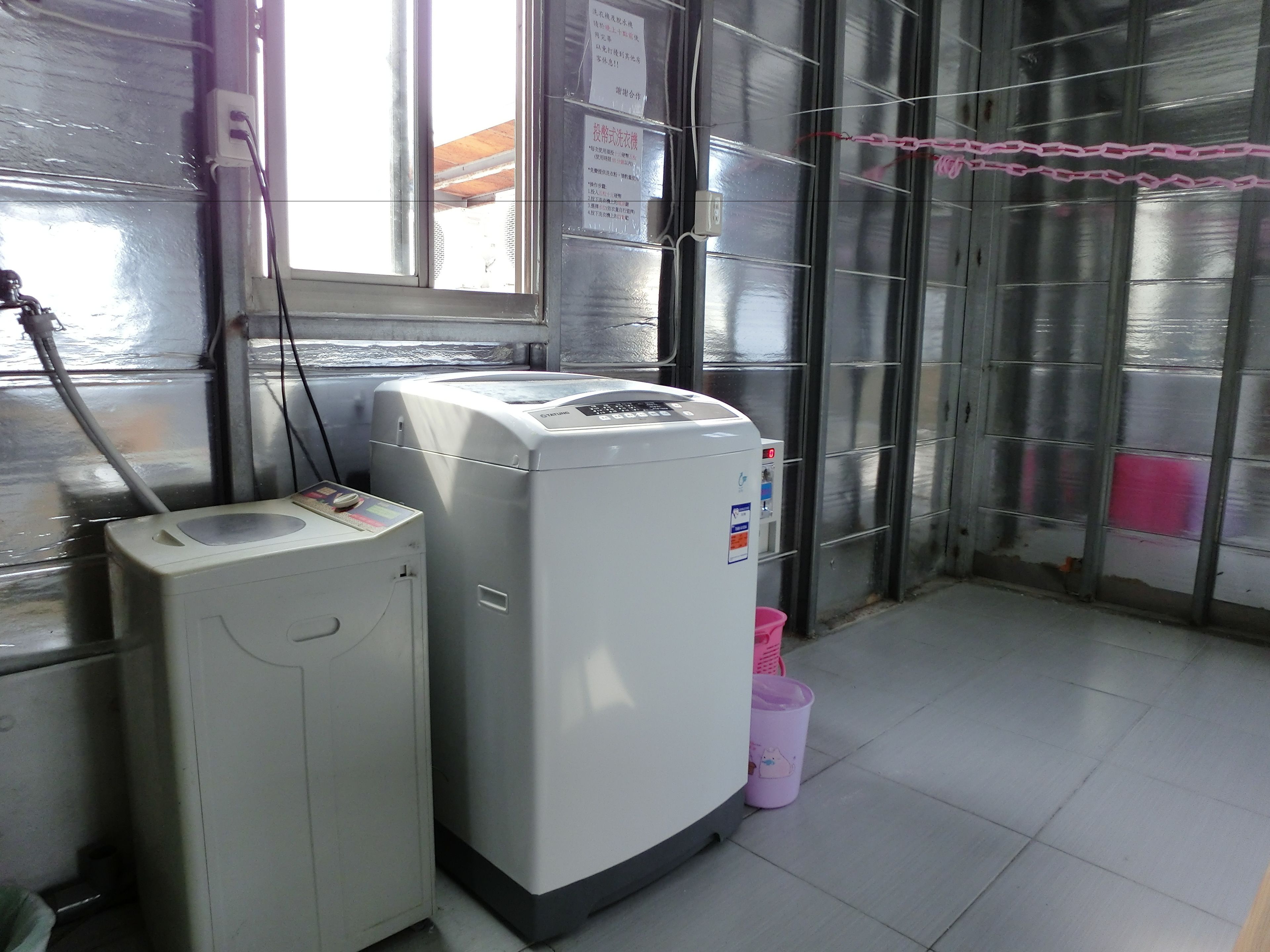 A laundry area with a washing machine and dryer, a window with a view, and a metal door.