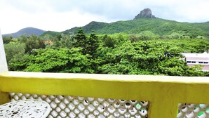 Un balcon avec une balustrade jaune et une table blanche ornée de motifs floraux.