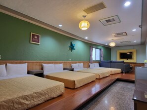A hotel room with three beds, a television, and a star decoration on the wall.