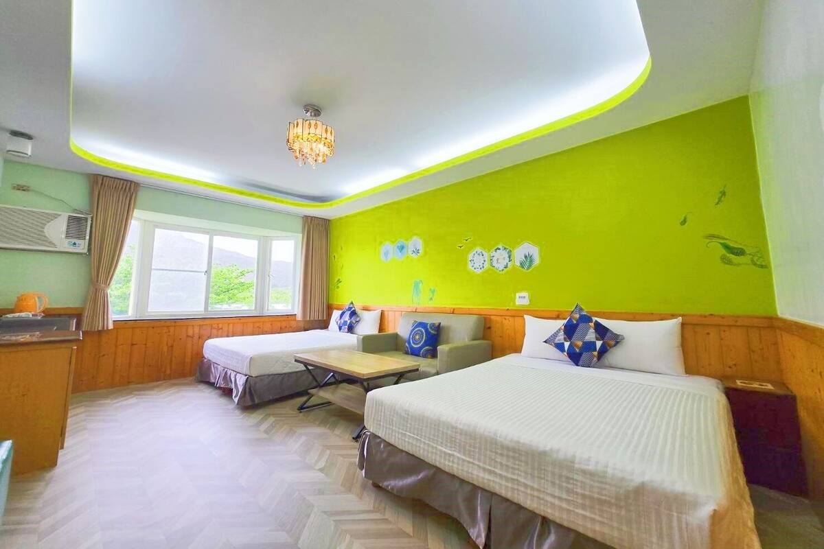 Quarto de hotel com duas camas, uma mesa e uma janela.