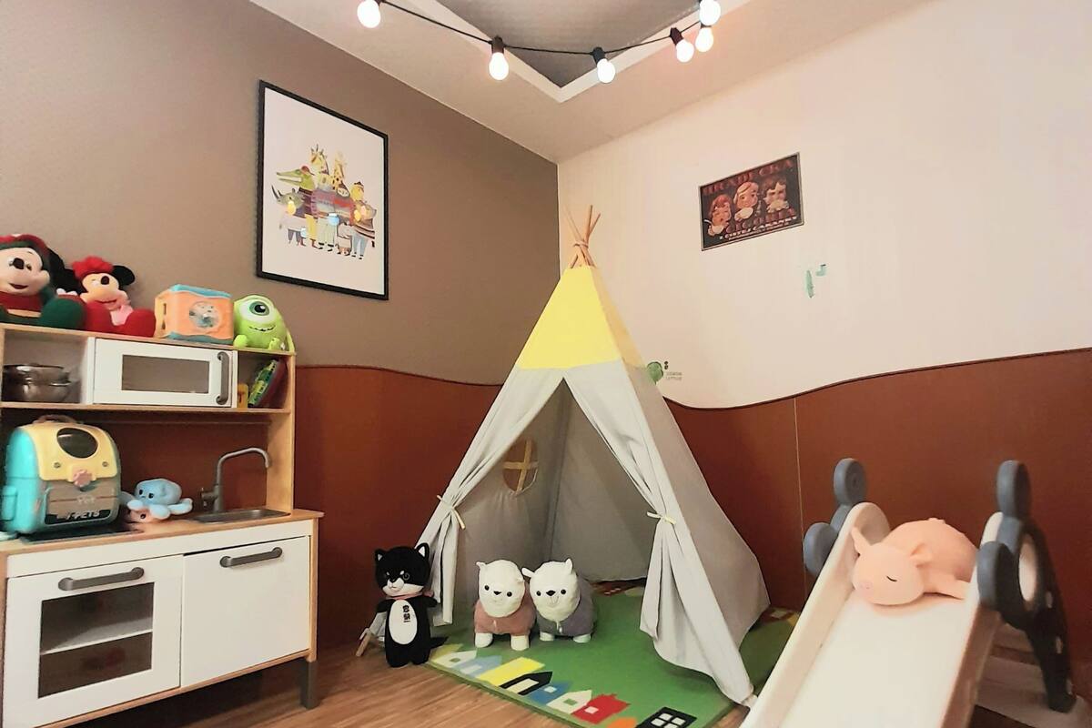 A child's playroom with a tent, a slide, and toys on shelves.