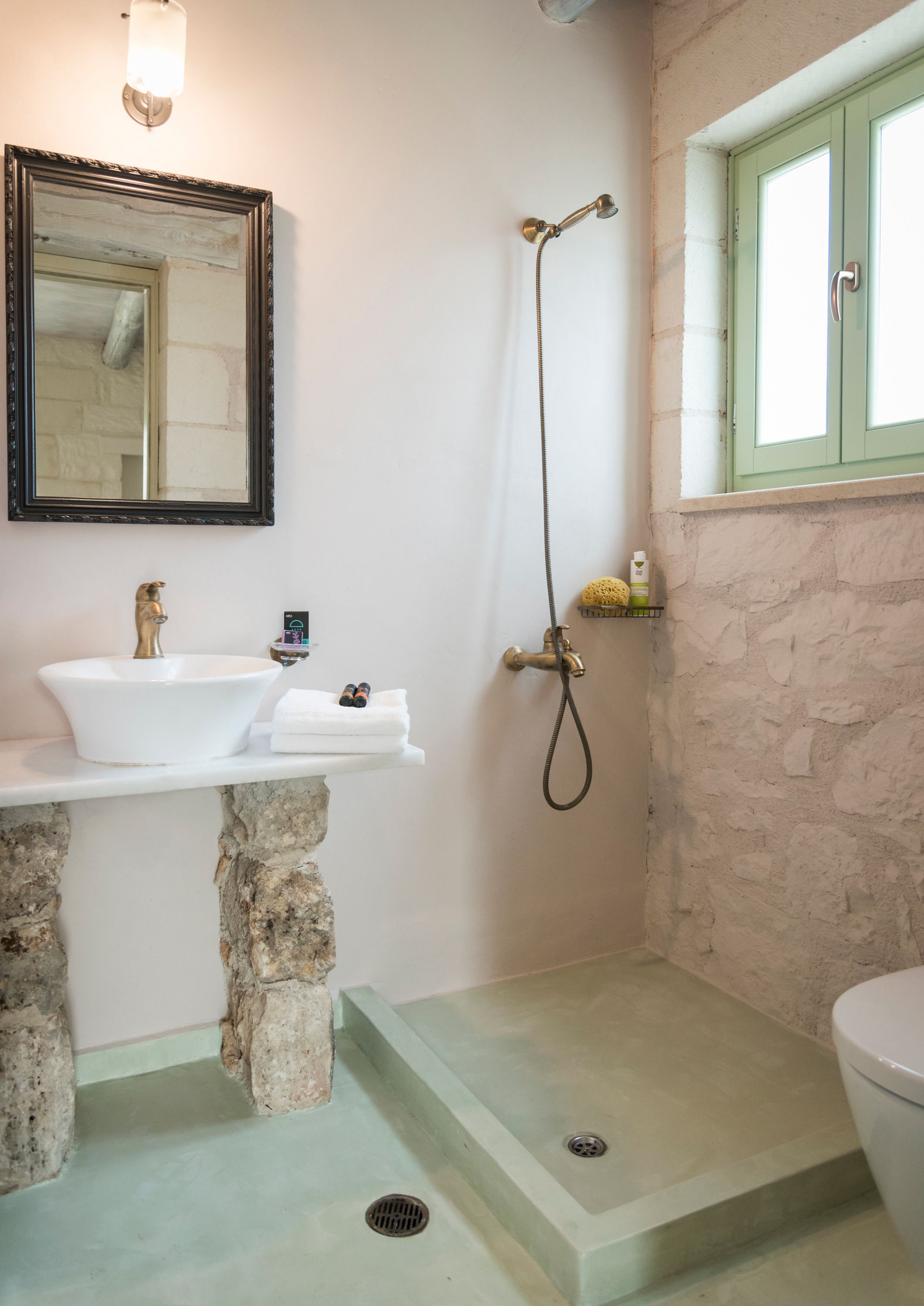A bathroom with a stone sink, a shower, and a toilet.