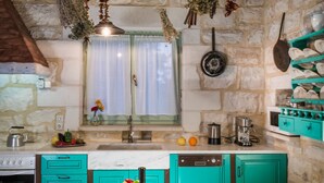 A kitchen with teal cabinets, a long countertop, and hanging dried herbs. - Boutique Villa Petra Amanda (Apokoronas)