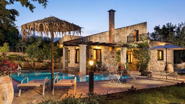 A stone house with a swimming pool, outdoor seating, and a thatched roof structure. - Boutique Villa Petra Amanda (Apokoronas)