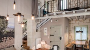 A spacious living area with a high ceiling, exposed wooden beams, a staircase, and a dining area. - Boutique Villa Petra Amanda (Apokoronas)