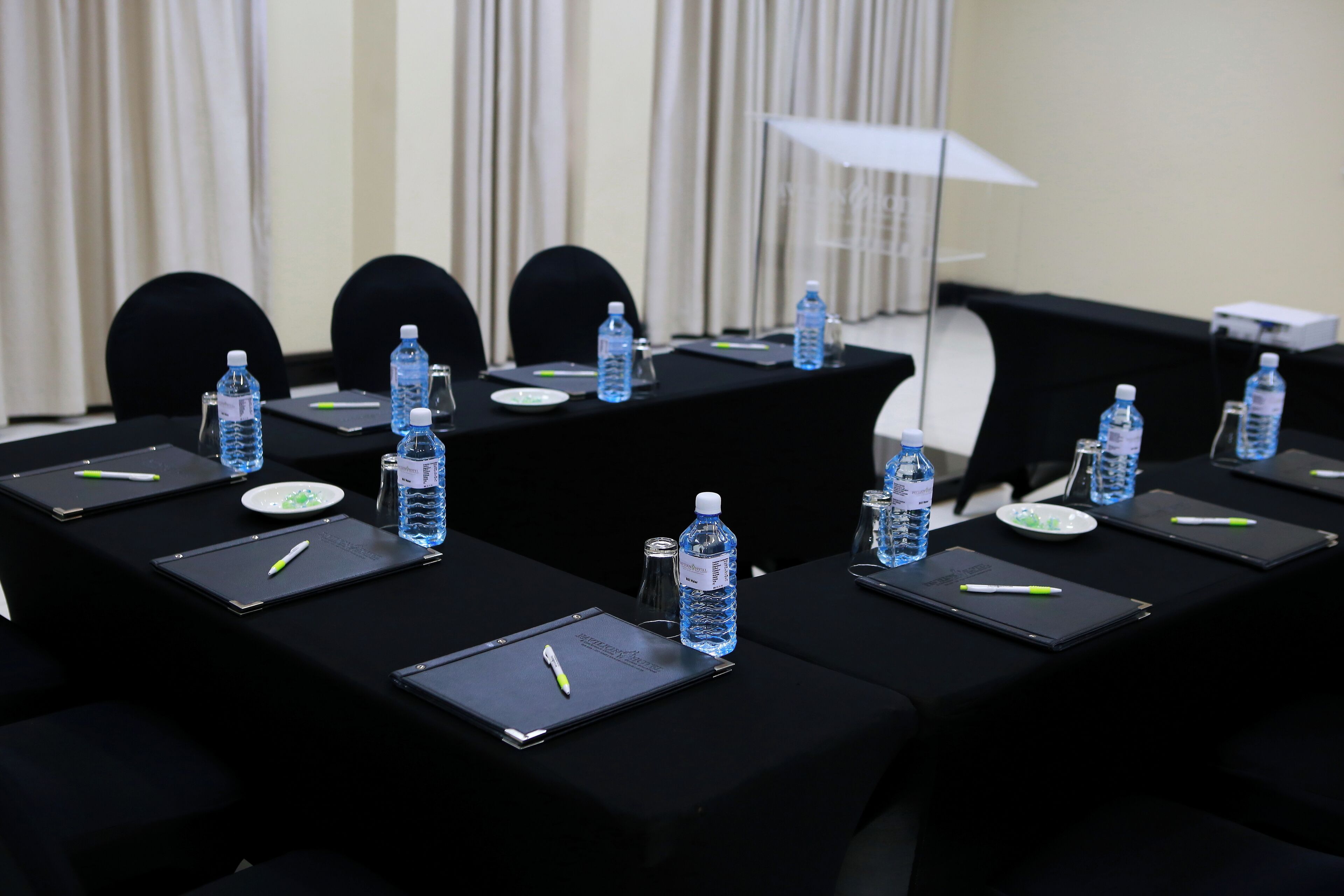 A conference room with tables set up for meetings, each with water bottles, notepads, and pens.