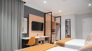 Una habitación de hotel con dos camas, un escritorio, una silla, un televisor y un armario.