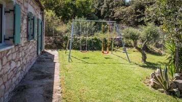 Escape to a serene family-friendly haven with a lush lawn and a charming stone building.