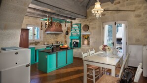 A kitchen with teal cabinetry, a central island, and a dining area with white chairs.