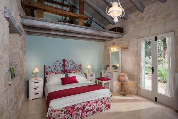 A bedroom with a bed, nightstands, a dresser, a mirror, and a door leading to an outdoor area.