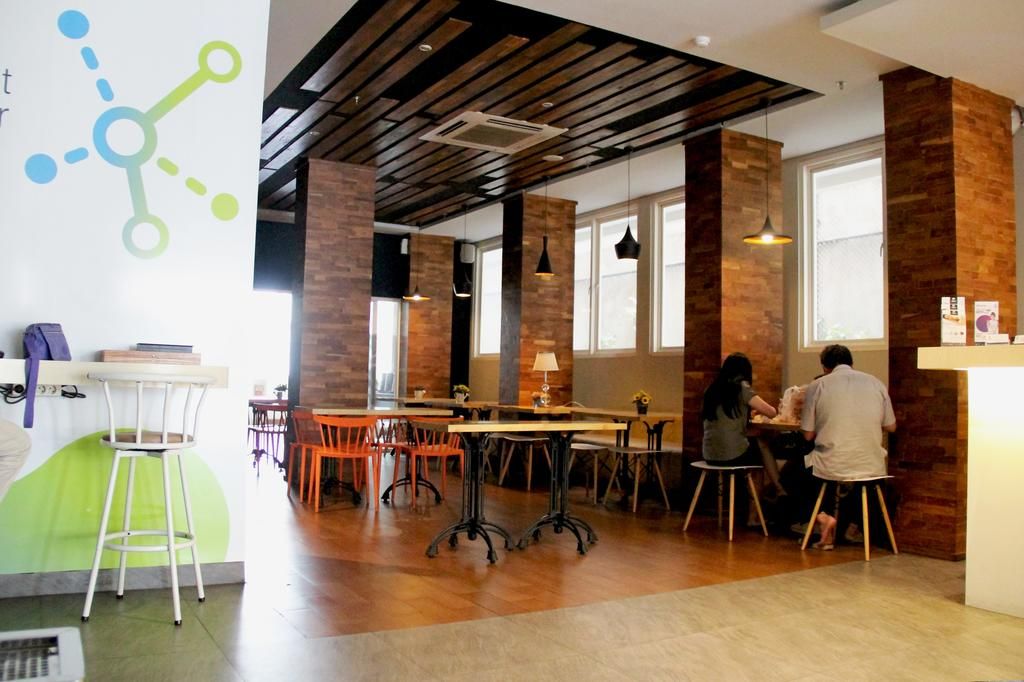 A modern office space with exposed wooden beams, large windows, and a mix of metal and wooden furniture.