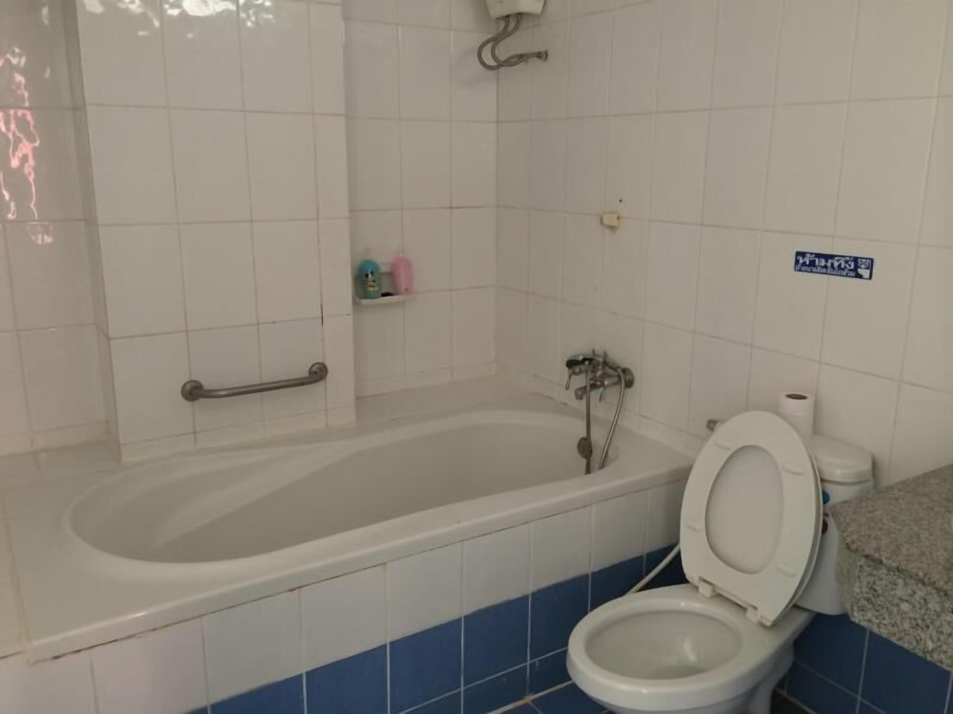 A bathroom with a bathtub, toilet, and a handrail.