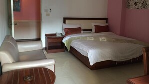 Een slaapkamer met een bed, een nachtkastje, een stoel en een kleine tafel.