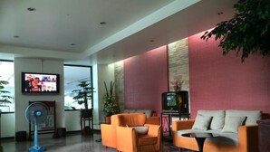 Een moderne lobby met een zithoek, een televisie en een ventilator.