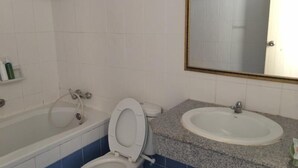 Een badkamer met toilet, wastafel en bad.