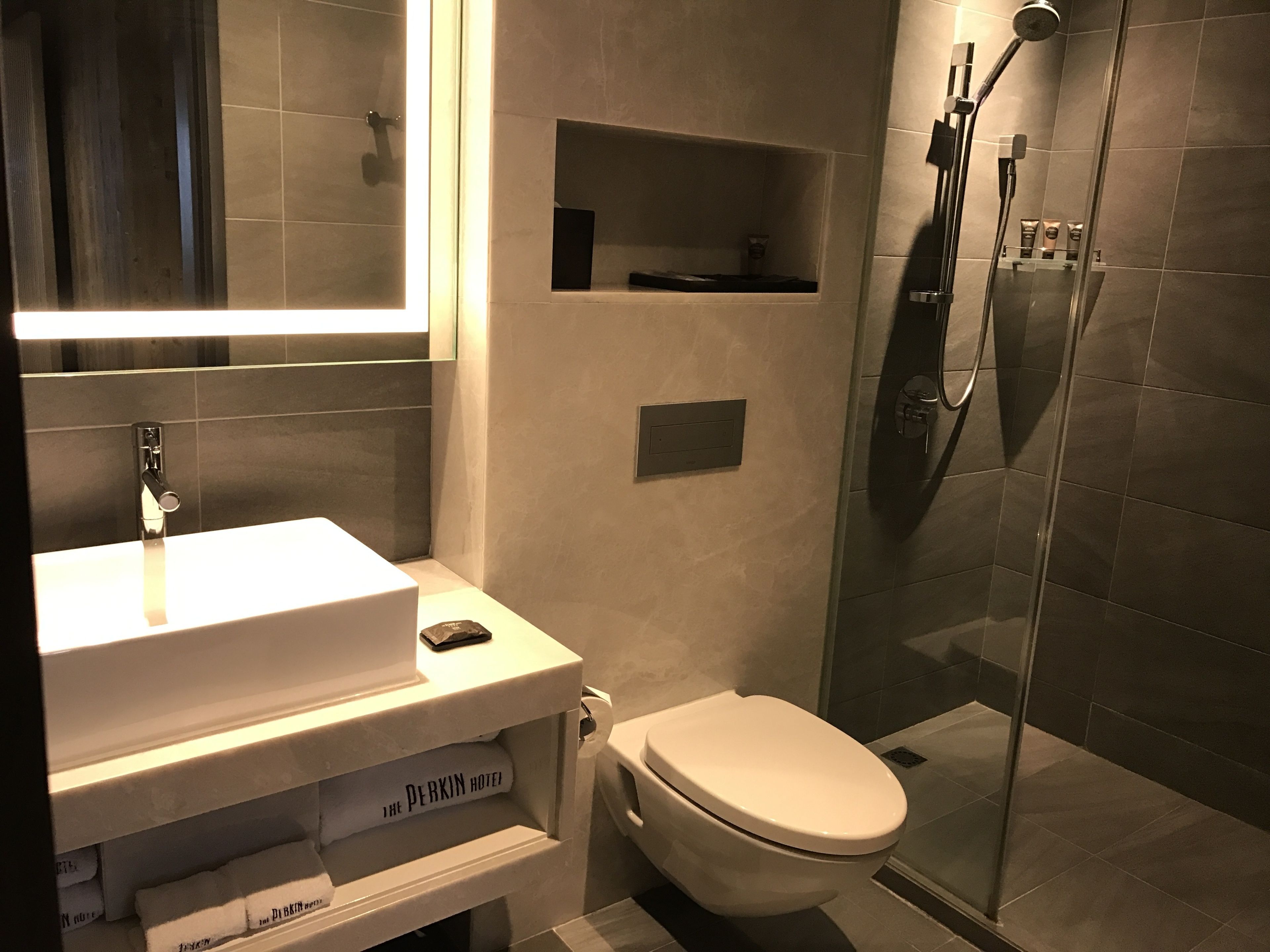 Un bagno moderno con lavandino bianco, un water e zona doccia con pareti in vetro.