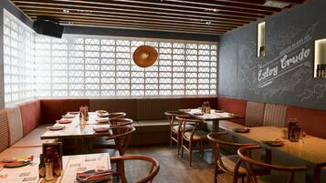L'intérieur d'un restaurant, avec des banquettes, des tables et un mur décoratif orné de motifs textuels.