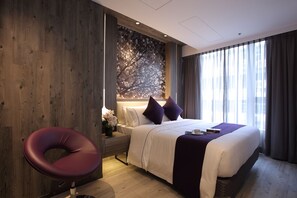 A modern hotel room with a large bed, a wooden accent wall, a dark-colored chair, and a large window with curtains. - The Perkin Hotel (Kowloon)