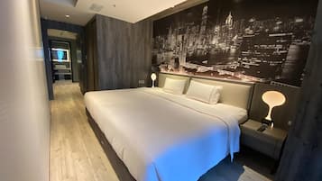 Habitació d'hotel moderna amb un llit gran, un mural de paisatge urbà a la paret i un sòl de fusta.
