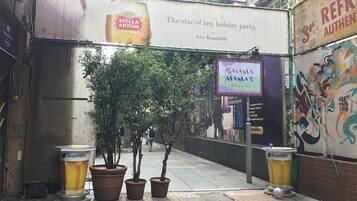 A street with a large billboard advertising Stella Artois beer, a Bahama Mama's Caribbean bar, and potted plants along the sidewalk.