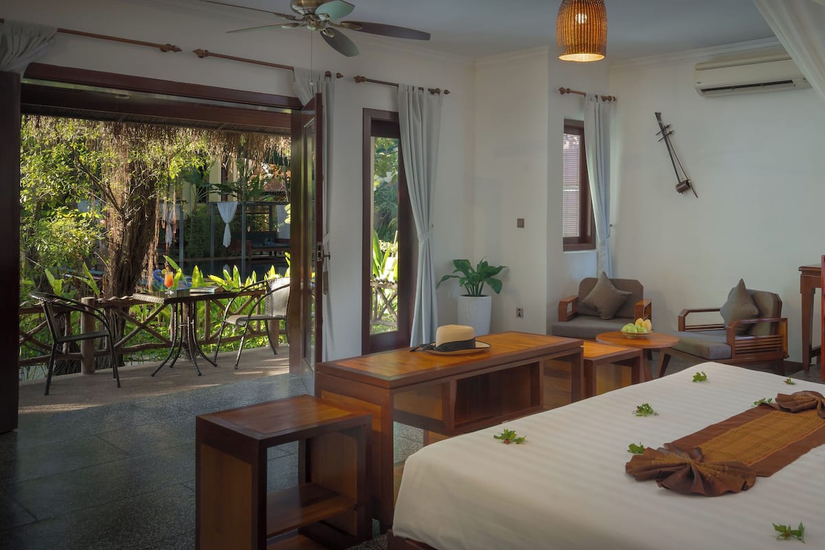 Une chambre d’hôtel comprenant un lit, un bureau, une chaise, une table et un balcon aménagé avec du mobilier d’extérieur.