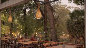 An outdoor seating area with tables and chairs, hanging lights, and trees. - La Rivière d' Angkor Resort (Siem Reap)