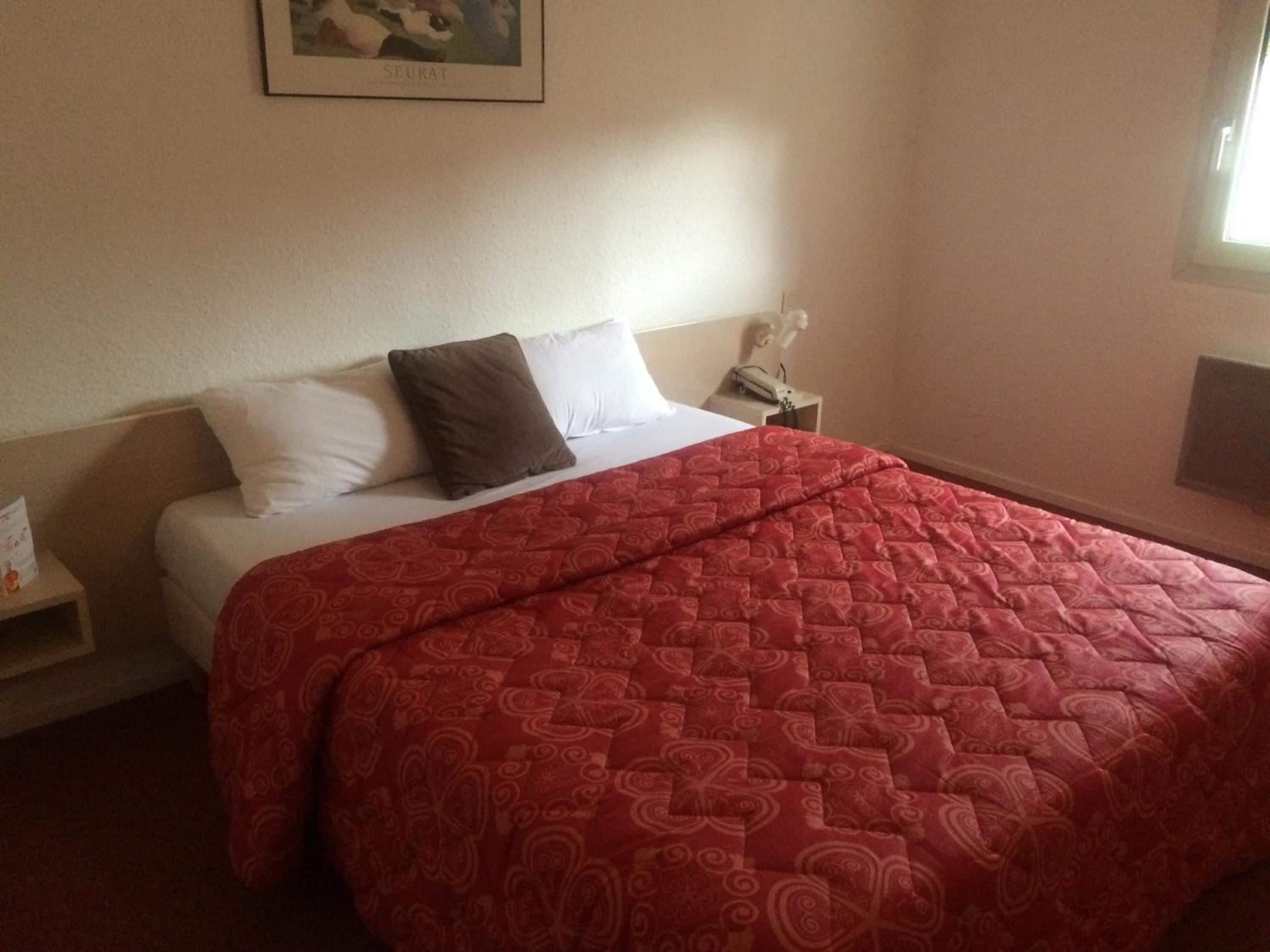 Una habitación de hotel con cama, mesita de noche, un cuadro en la pared y una ventana.
